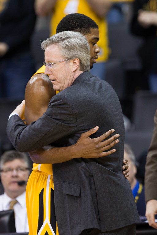 Basketball player and coach embrace.