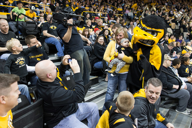 Woman posing with Iowa's mascot Herky in the crowd.