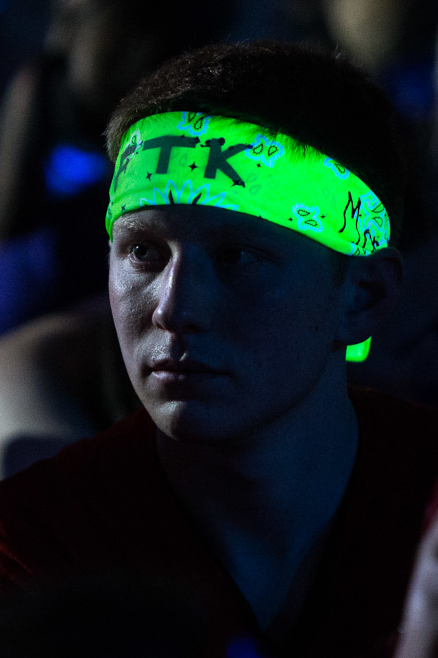 A young man wearing a flourescent green headband with the letters F.T.K. written on it with a marker.