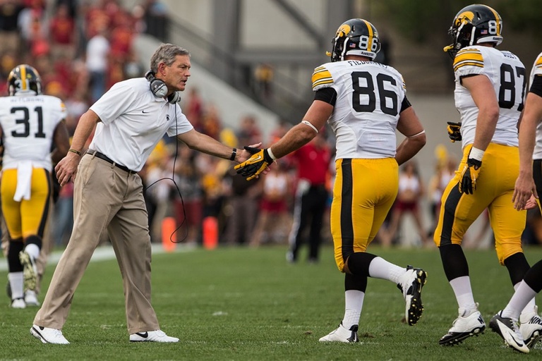 Football coach gives a low five to a player.