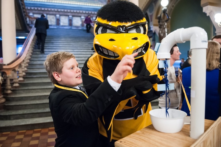 A young child looks at a display with Herky.