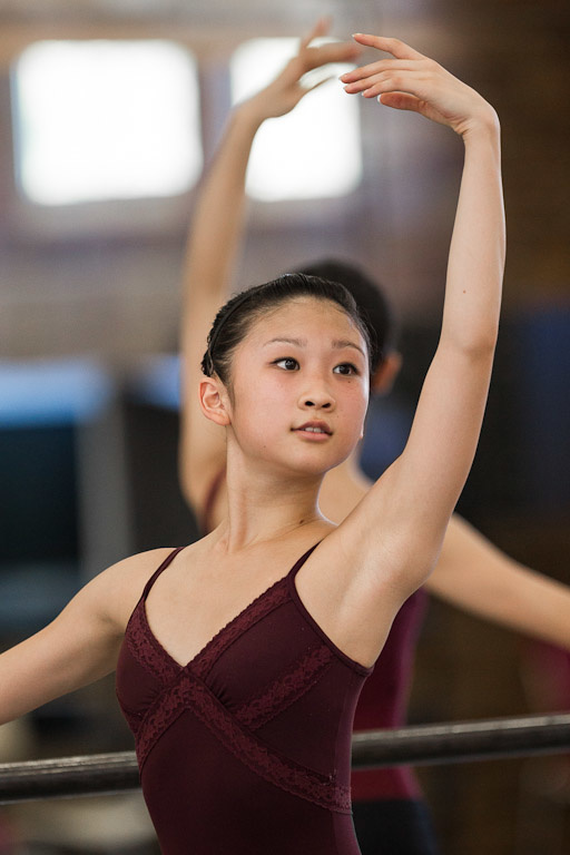 A female dancer poses with her left arm in the air.