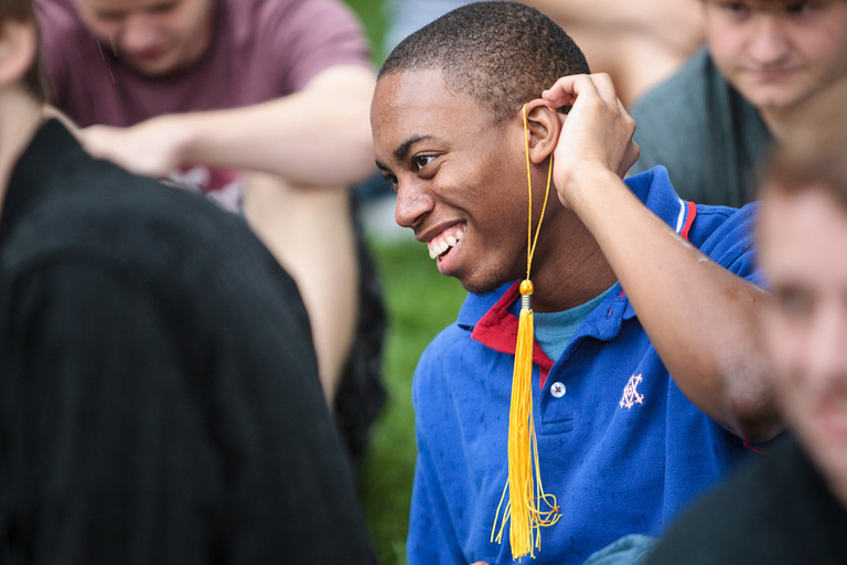 Student wraps graduation tassel around his ear.