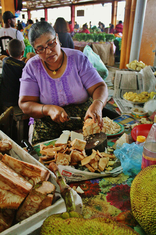 woman prepares jackfruit to sell at a market