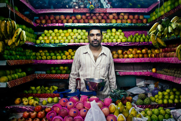 A man stands in the middle of a fruit stand in a market in Mumbai, India