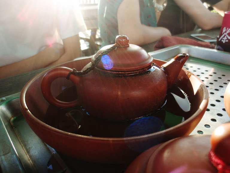 A close up photo of a maroon-colored teapot in a bowl in Taipei, Taiwan.