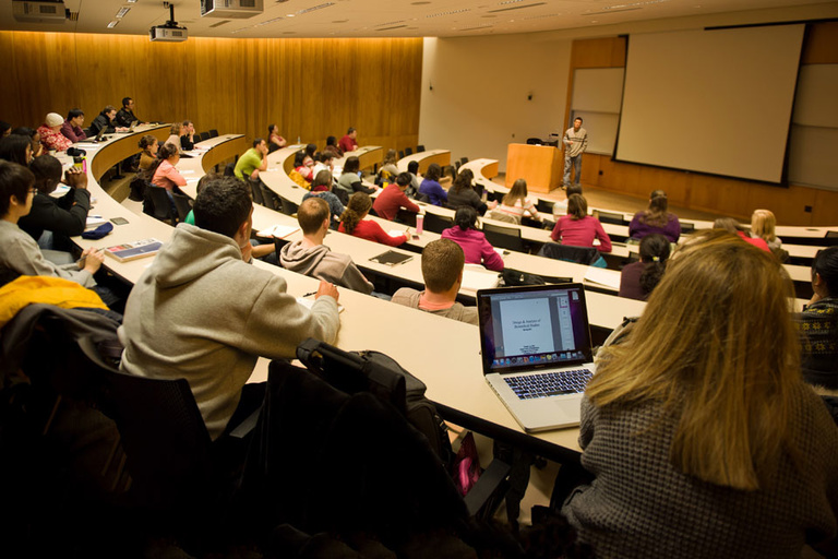 Students attend class in a large lecture room.