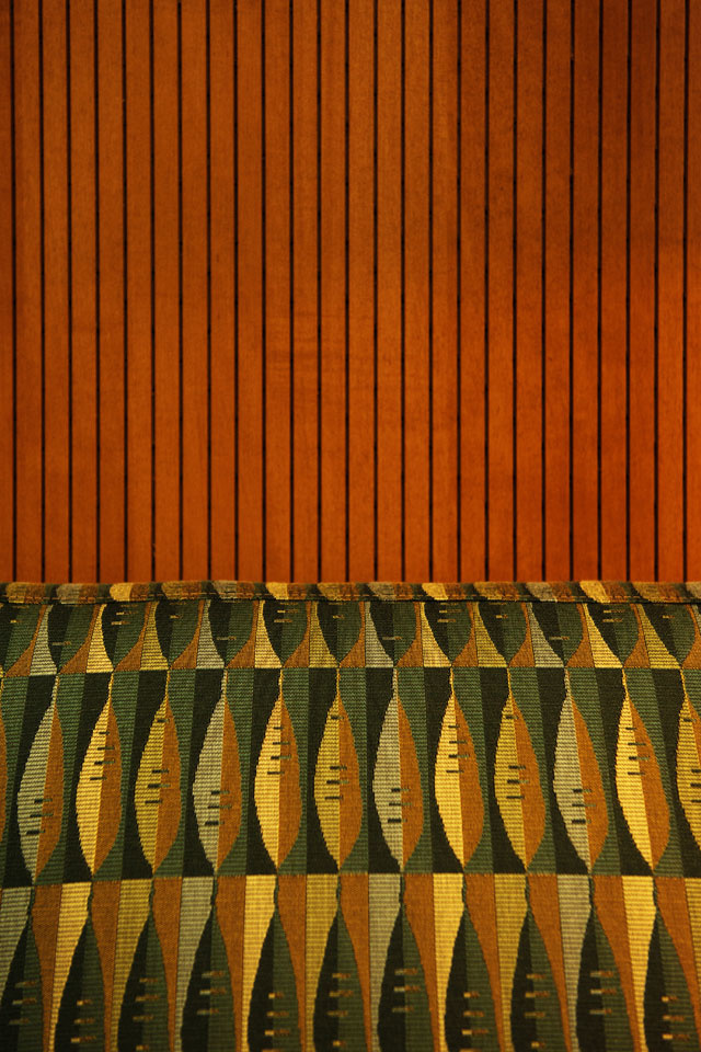 Detail of grooved wood paneling and abstract leaf printed upholstery. 