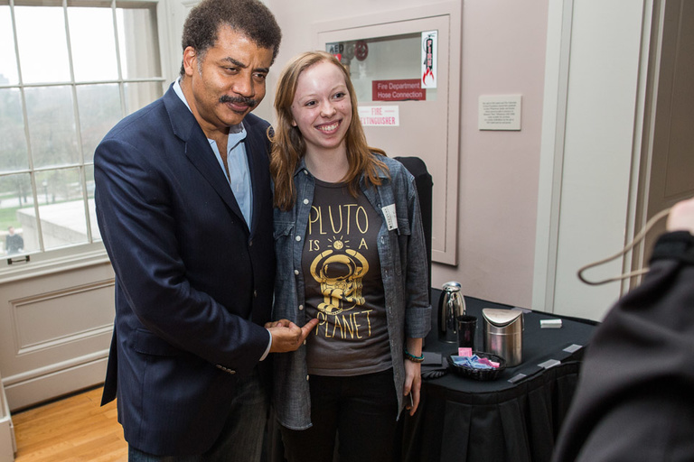 A man and a young woman wearing a t-shirt saying "Pluto is a Planet" pose for a photo.