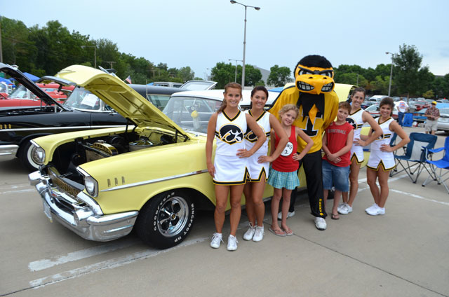 Herky and cheerleaders pose next to a vintage car