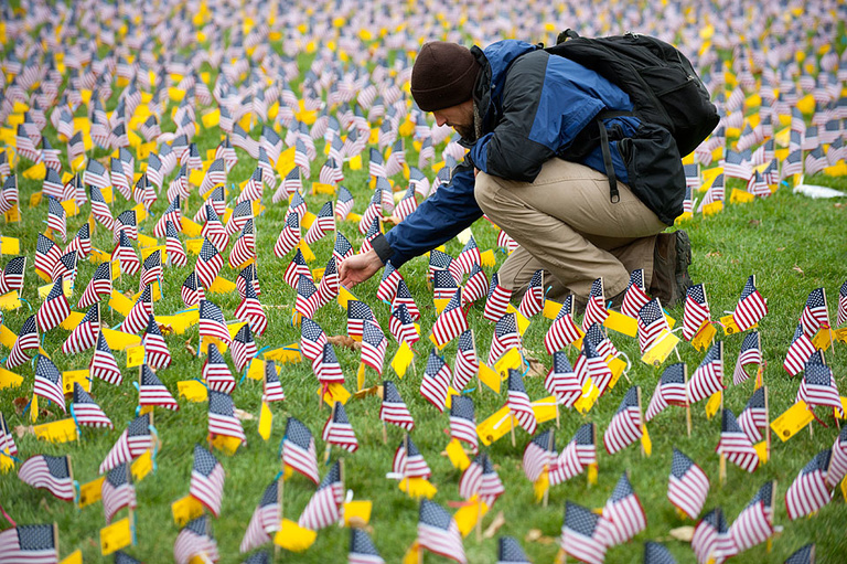 Zach Carter, a student and veteran, examines the names on the flags.