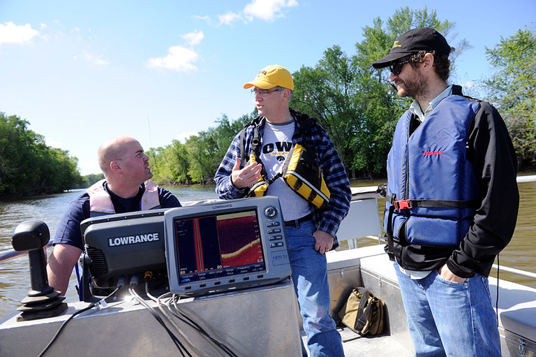 Brad Reuter, Doug Schnoebelen, and Andres Martinez on a boat on the Mississippi River.