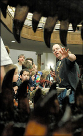 Photo of man and children view through the teeth of a dinosaur model
