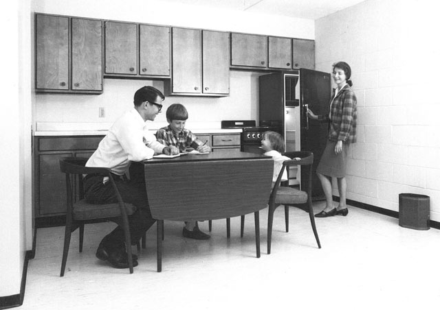 Black-and-white photo of a family in the kitchen at Hawkeye Court apartments circa 1968