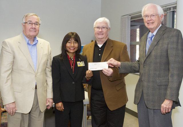Four people, one holding a donation check