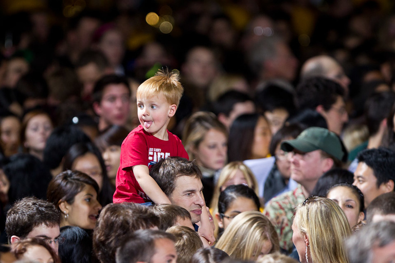a boy sits on an adult's shoulders inside the field house