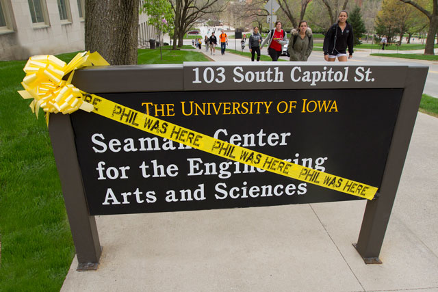Phil Was Here caution tape wrapped around a campus building sign