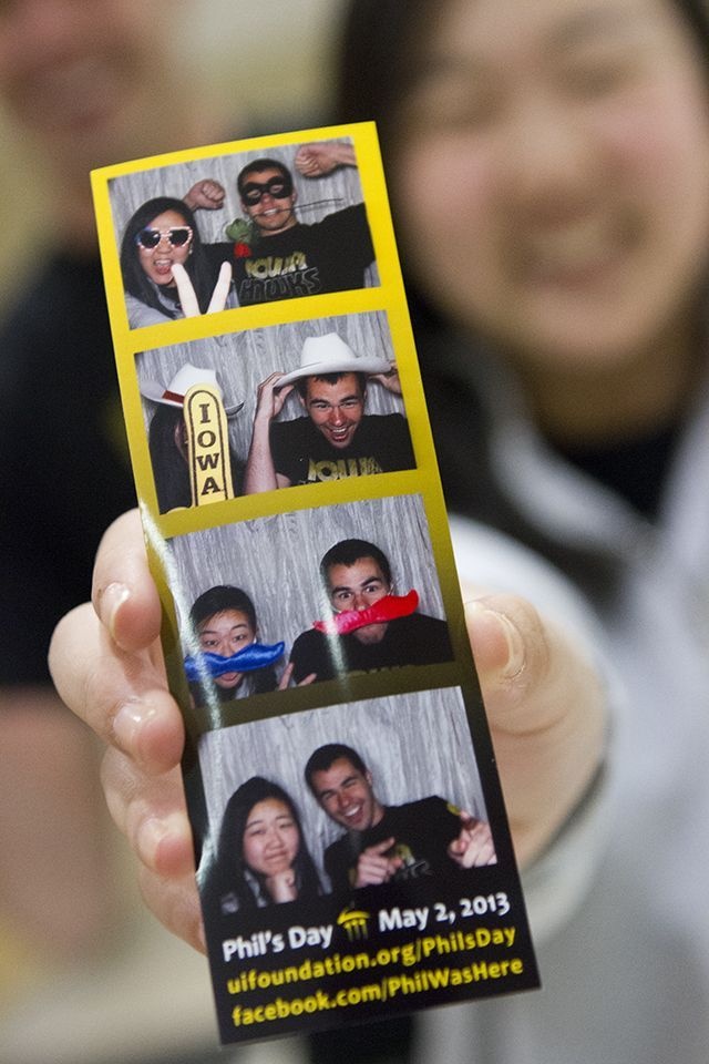 Someone holds up a series of photos taken in a photo booth as part of Phil's Day activities. 