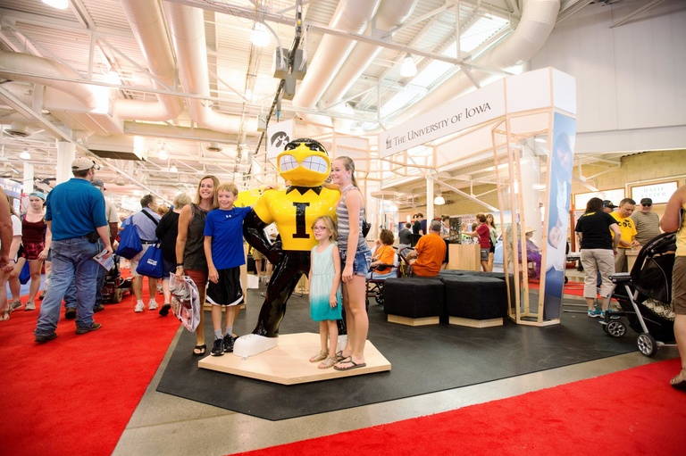 A family poses with Herky, the UI mascot, at the UI State Fair booth.