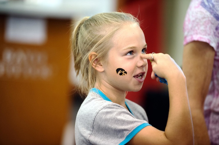 a girl with a tigerhawk tattoo on her cheek points to the bridge of her nose