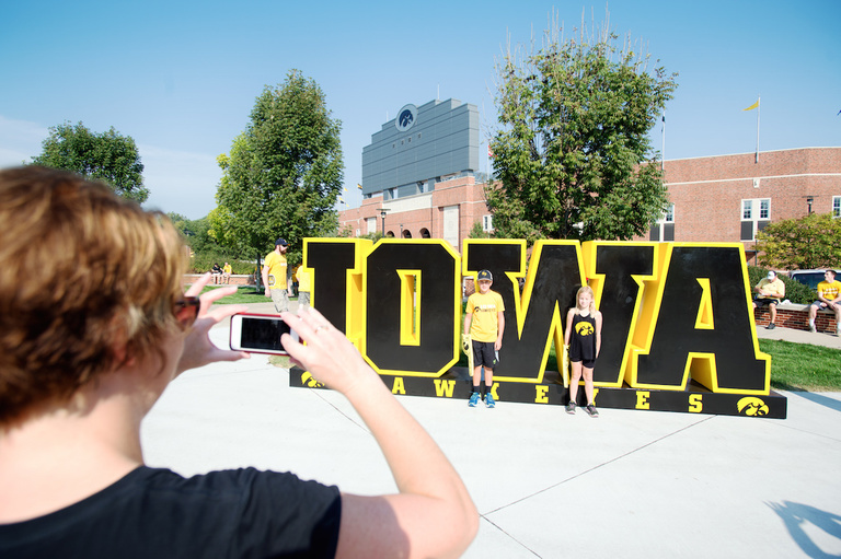 Woman taking photo of kids in front of IOWA sign.