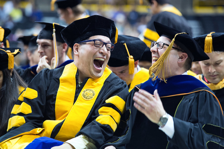 Graduate and professor laughing together at commencement ceremony
