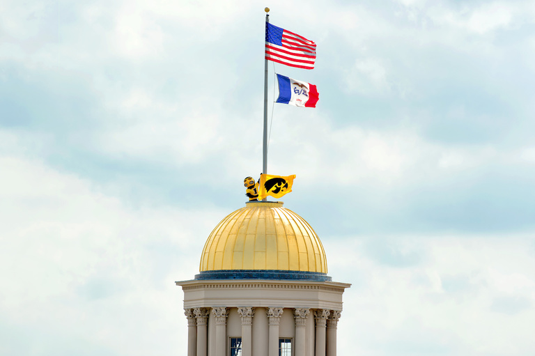 Herky atop Old Capitol holding Hawkeye flag