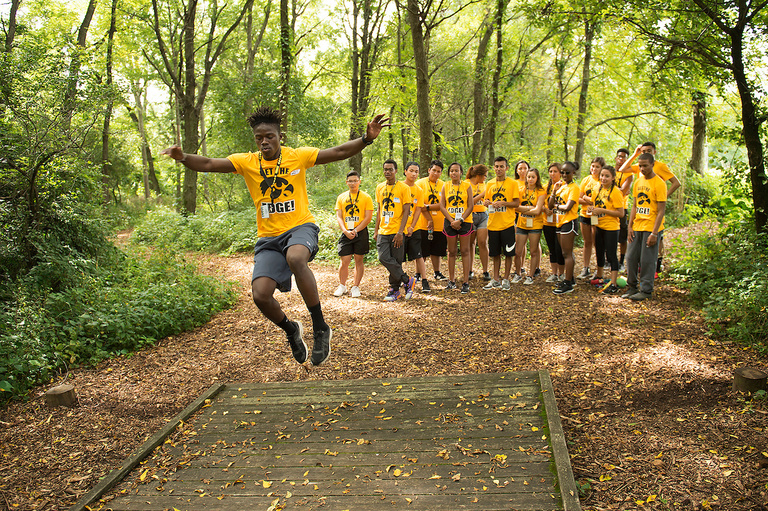 Student in gold t-shirts completing an exercise in wooded area