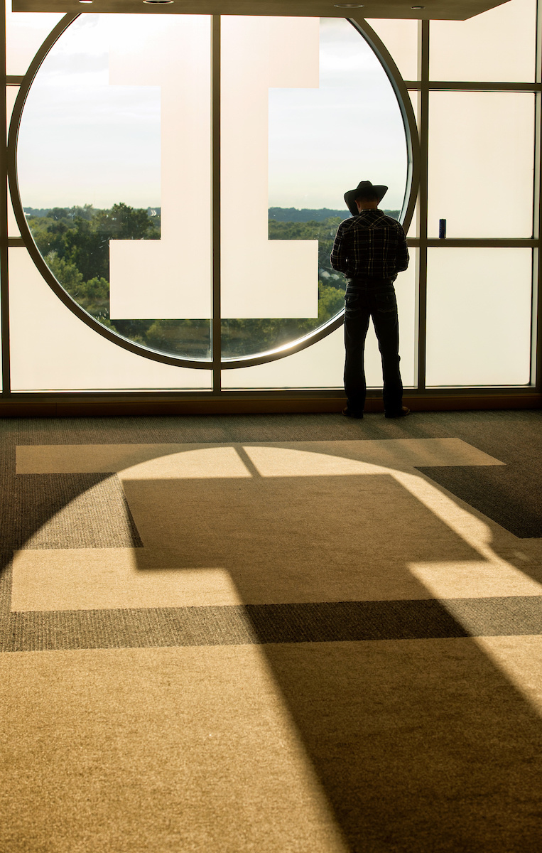 Man in cowboy hat silhouetted by light coming through large window
