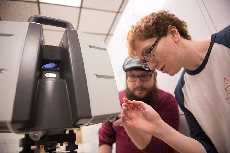 Adam Skibbe (red shirt), Zachary Luppen (Black shirt), and Drew Hutchinson (white shirt) use a LiDAR scanner to make a 3-D scan of the Tilden Meteorite, which landed in Illinois in the 1920s.