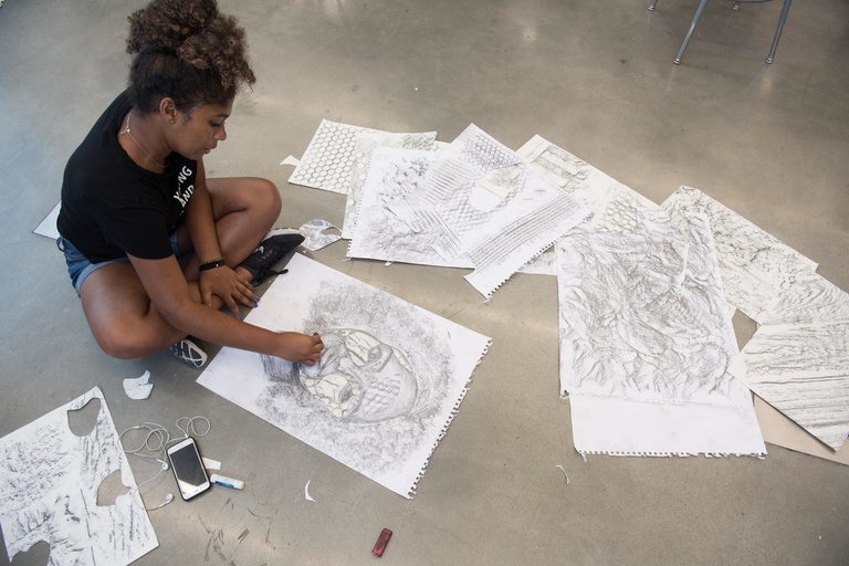 student sitting with multiple sketches