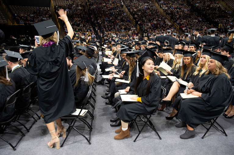 seated graduates with one standing and waving