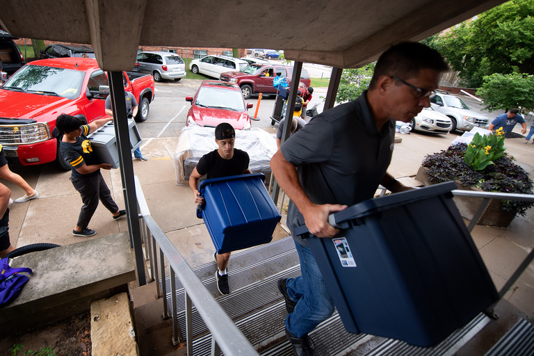 people carrying plastic tubs during on iowa move-in