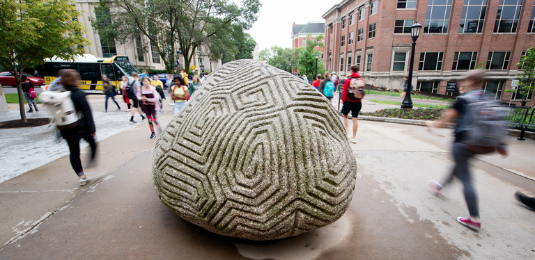 students passing sculpture