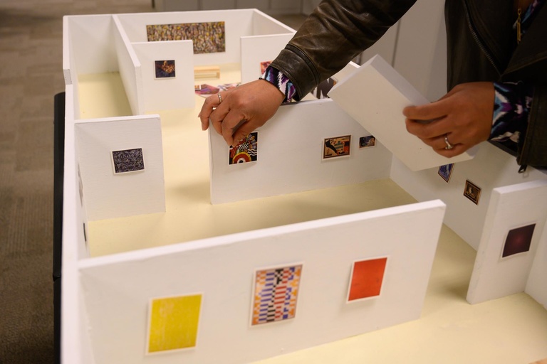 curator adjusts miniature art pieces in model museum gallery