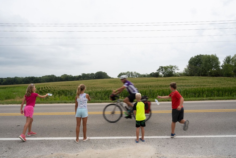 kids offer water to a cyclist