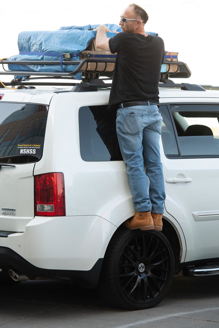 parent retrieving luggage from roof rack