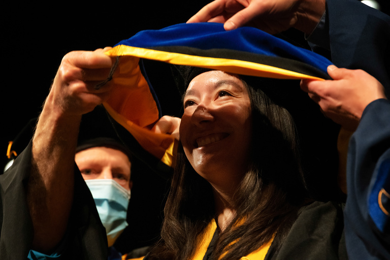 A Doctoral graduate receives their hood during the commencement ceremony. Photo by Justin Torner.