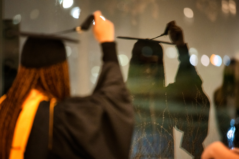 A Master's candidate adjusts their tassel before her commencement ceremony. Photo by Justin Torner.