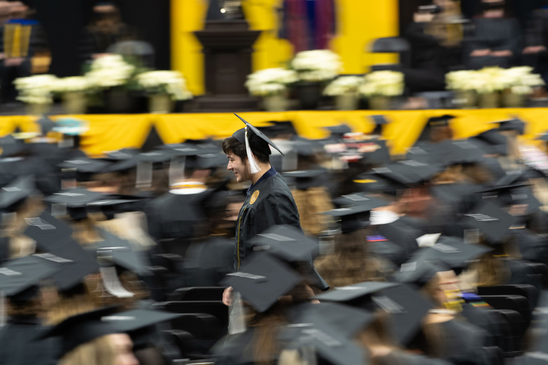 A College of Liberal Arts and Sciences graduate makes their way back to their seat after being individually recognized on stage. Photo by Tim Schoon.
