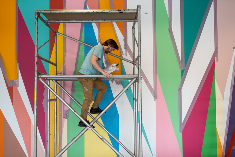 Conor Fields works on "Surrounding," a mural located in the UI Stanley Museum of Art. The mural was created by artist Odili Donald Odita.