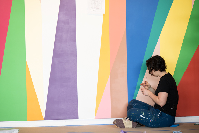 Painter Jenna Pirello works diligently on a lower section of the mural, "Surrounding," located in the lobby of the UI Stanley Museum of Art.