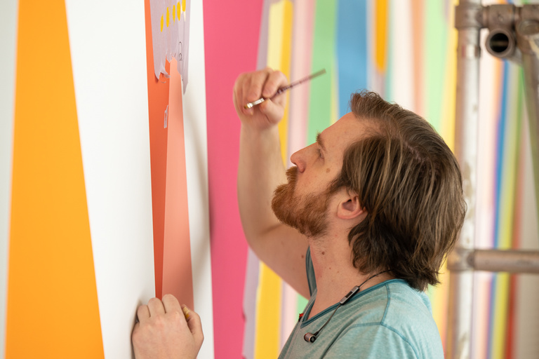 Painter Conor Fields keeps a close eye on the task at hand while working on "Surrounding," a mural by artist Odili Donald Odita located in the lobby of the UI Stanley Museum of Art.