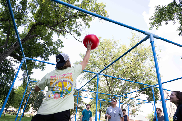 A student lifts the ball in the air during a game of 9 Square on the Pentacrest.