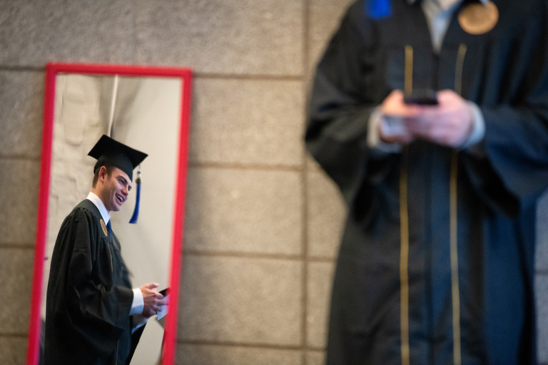 A graduate looks in the mirror before the Tippie College of Business commencement ceremony.