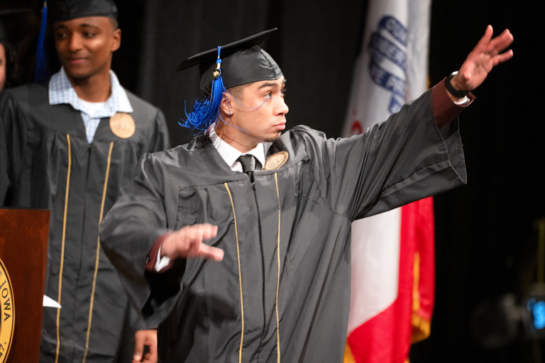 A graduate salutes his family while leaving the stage during the Tippie College of Business commencement.
