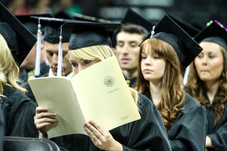 graduate reads during commencement ceremony