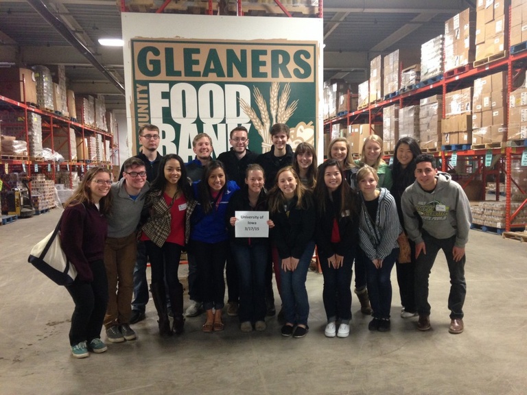 A group of students stand in front of a Gleaners Community Food Bank sign.