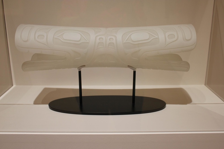 Soul Catcher, by Tlingit artist Preston Singletary, is a translucent glass sculpture that takes the title, form, and style of bone and ivory amulets worn by shamans among the Indigenous people of the Pacific Northwest coast. This sculpture has two heads j