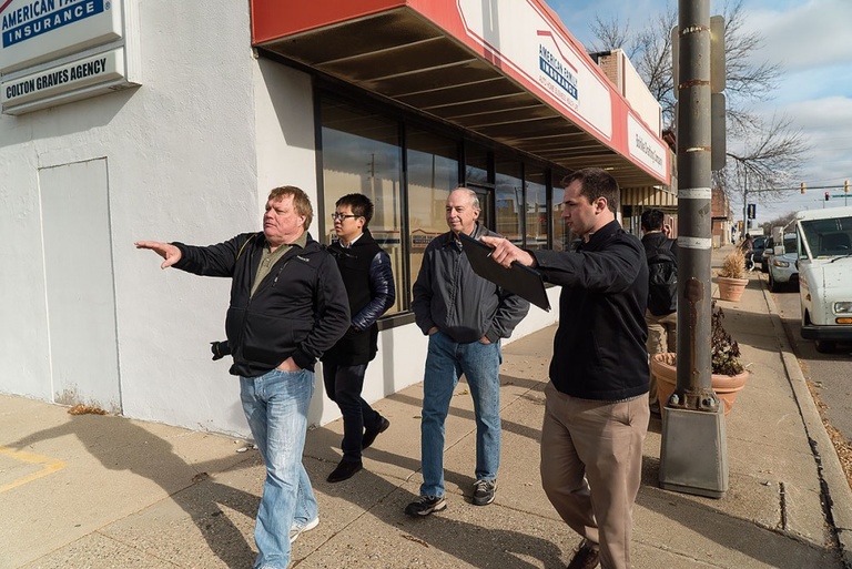A group of men walk down a street in Sioux CIty in the Leeds neighborhood, pointing out special attractions.